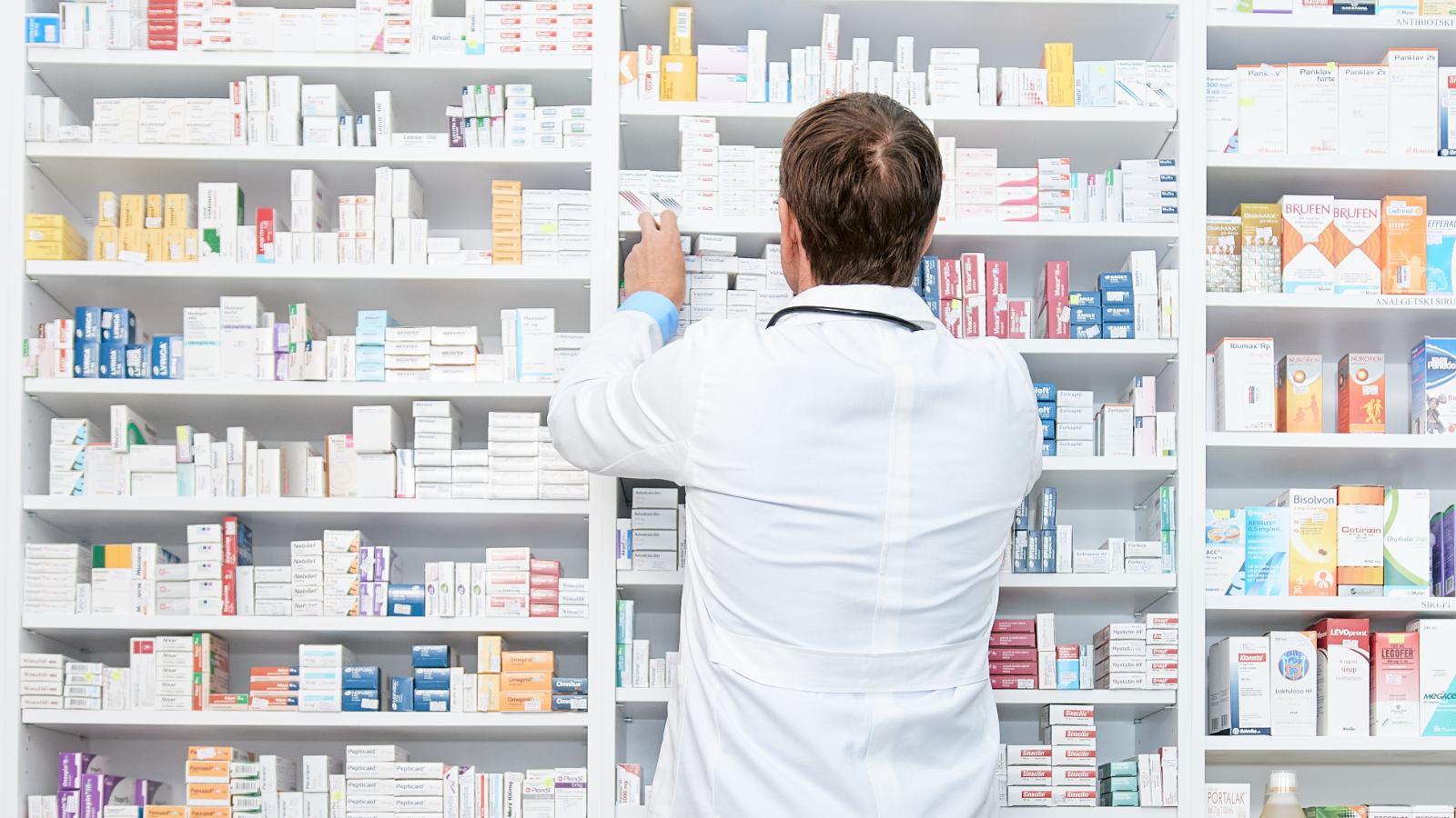 Apotheker vor den Medikamentenregalen der Offizin