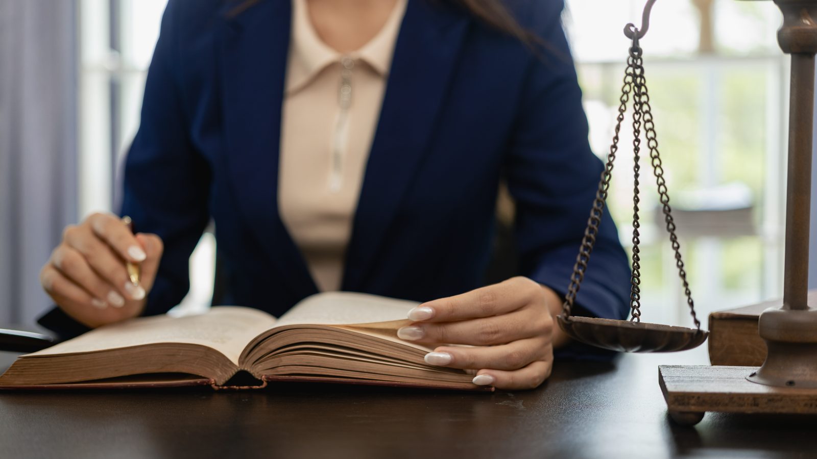 Juristin mit aufgeschlagenem Gesetzbuch und der Waage der Justitia