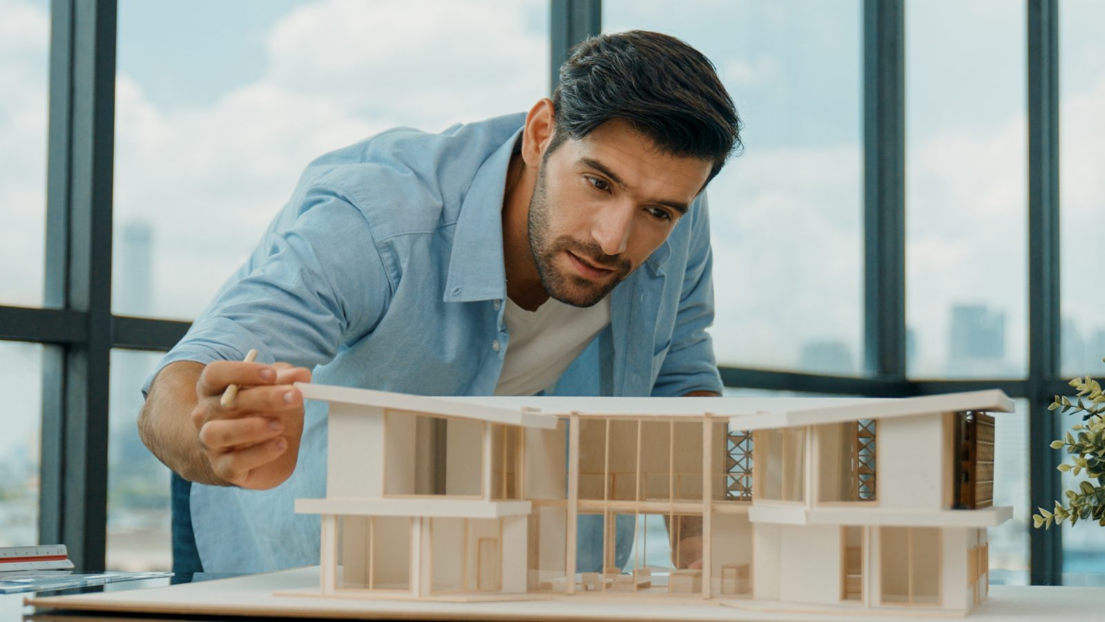 Architekt prüft ein Gebäudemodell am Fenster